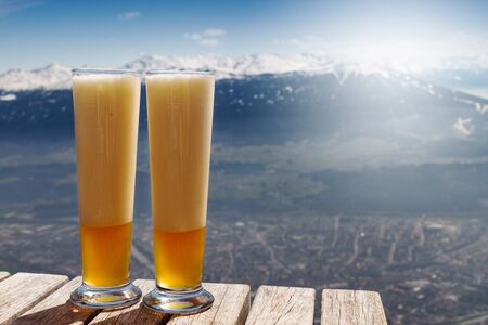 Tasty beautiful cold beer on a wooden table on mountain background. Beautiful landscape. Alps mountains. Austria.の写真素材