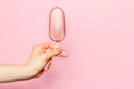 Hand of young woman holding ice cream on pink background. Fashion Background. Summer Concept.の写真素材