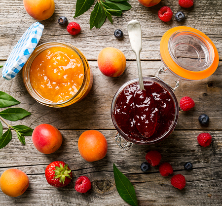 Tasty fruit red strawberry berry jams in glass jar with fruits on wooden table. Closeup. Top View.