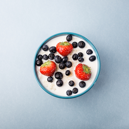 From above view of bowl with oatmeal served with blueberries and strawberries on blue. の写真素材