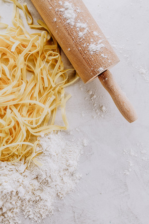 Tasty fresh appetizing raw pasta with flour and eggs on bright table. Top View.の写真素材