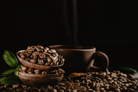 Composition of wood bowls filled with coffee roasted beans and arranged with cup and green leaves.の写真素材