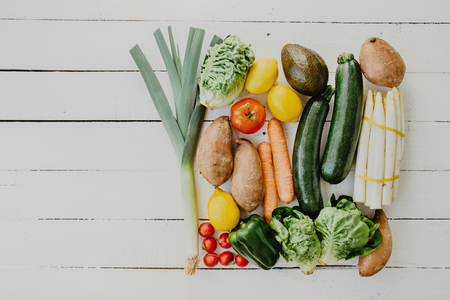 Flat lay of arranged fresh vegetables lying in order on white wood.の写真素材