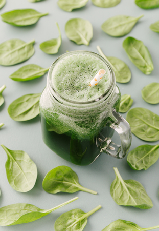 From above glass jar with refreshing green drink on background of spinach pattern. の写真素材
