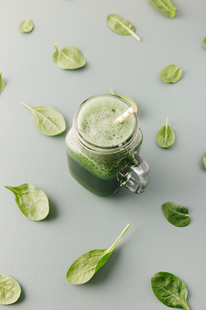 From above glass jar with refreshing green drink on background of spinach pattern.の写真素材