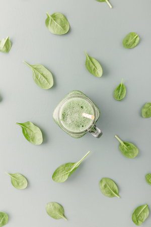 Top view of glass jar with green drink on table with leaves pattern.の写真素材