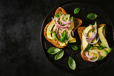 Fresh ready served avocado toasts with spices on dark table. Ready to eat. Closeupの写真素材