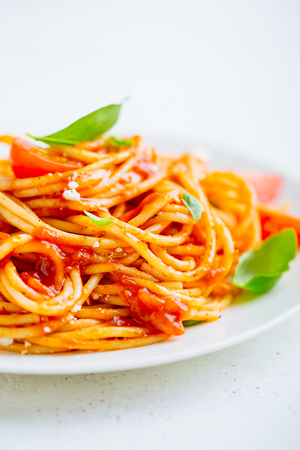 Appetizing italian pasta dish with tomato sauce on plate on white table. Closeupの写真素材