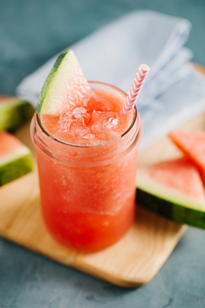 Fresh cold watermelon drink with ice and watermelon slices on blue table. Closeupの写真素材