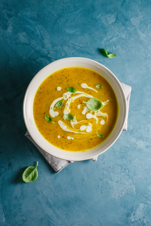 Tasty appetizing autumn soup with pumpkin and fresh cream in bowl served on table. Closeup view from aboveの写真素材