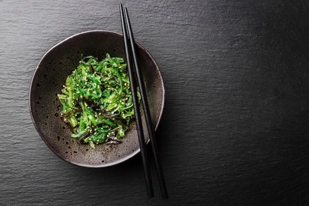Tasty appetizing seaweed salad on dark plate on slate background. Closeupの写真素材