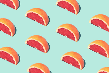 Beautiful food pattern, food fashion concept with half slices of grapefruit on turquoise background....