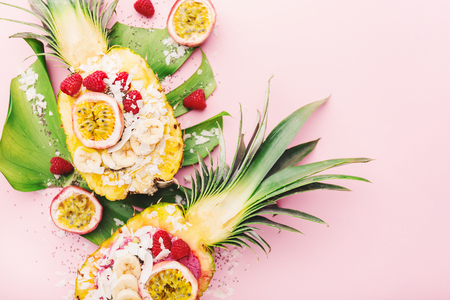 Tasty appetizing smoothie bowls served in half pineapple decorated with cut passion fruit, coconut flakes, and chia seeds.Healthy life clean eating concept. Top View. Horizontal.の写真素材
