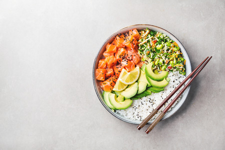 Tasty appetizing poke bowl served with salmon, avocado, rice, salad with edamame. Grey background. View from above with copy space.の写真素材
