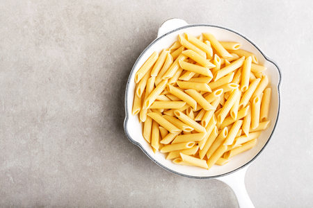 Cooked italian pasta penne served in white pan. Simple food. View from above with copy space. Grey background. の写真素材