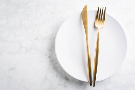 Beautiful gold cutlery - fork, knife on marble background. Horizontal.の写真素材