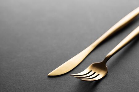 Beautiful gold cutlery - fork, knife on black background. Horizontal.の写真素材