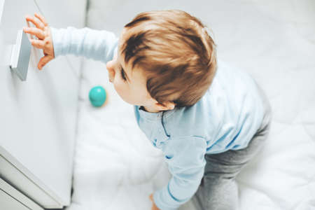 Curious baby boy touching door in the kitchen. Baby or safety baby concept.の写真素材
