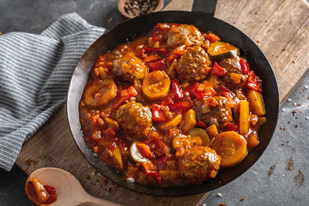 Meatballs with vegetables and sauce made in pan and served on table.の写真素材