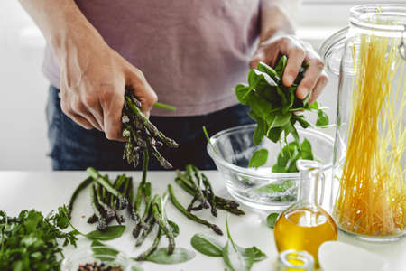 Man cooking or preparing asparagus and spinach for dinner at home. Clean eating.の写真素材