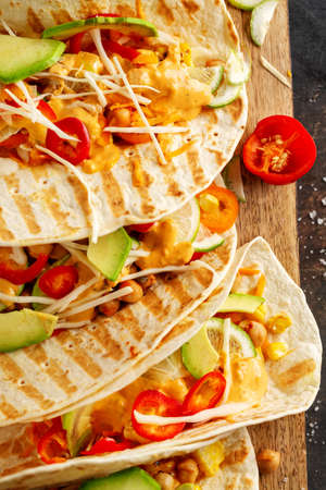 Tasty appetizing fresh homemade vegan tacos with chickpeas and vegetables served on board. Top view.の写真素材