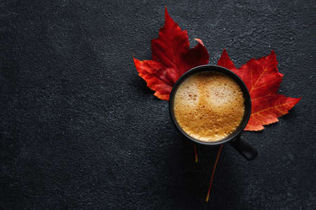 Autumn background with freshmade coffee in cup and maple leaves.