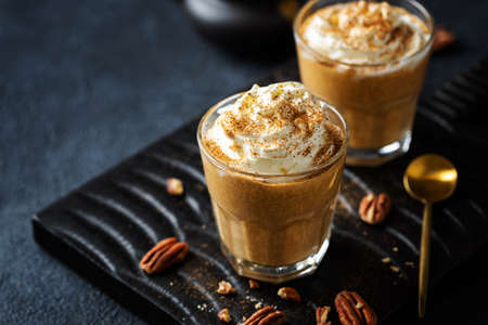 Autumn fall pumpkin smoothie drink with whipped cream and cinnamon. Served in glasses.の写真素材