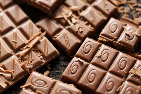 Broken chocolate bars on dark background. Closeup. Chocolate background