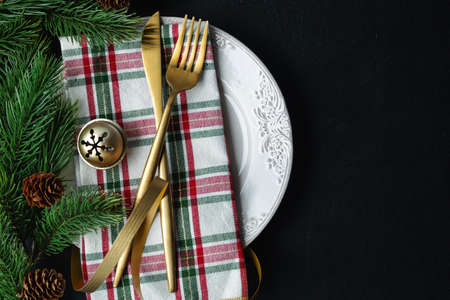 Christmas golden cutlery on plate with ribbon on dark background.の写真素材