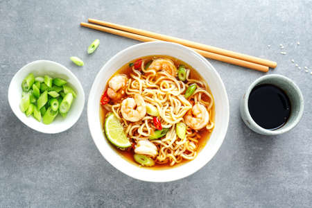 Tasty appetizing asian noodles with vegetables and shrimps in bowl on concrete background.