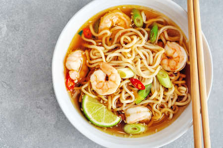 Tasty appetizing asian noodles with vegetables and shrimps in bowl on concrete background.の写真素材