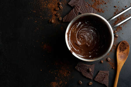 Melted chocolate in pot with chocolate pieces around on dark background. Top View.の写真素材