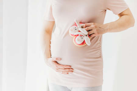 Pregnant woman holding small baby shoes. Lifestyle. Mothernity concept.の写真素材
