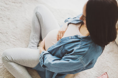 Pregnant woman sitting on the floor. Lifestyle. Maternity concept.の写真素材