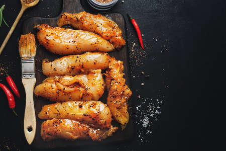 Raw marinated chicken breast on dark background with spices ready to cook.の写真素材