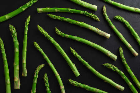 Green asparagus on dark background ready for cooking. Pattern mockup food backgroundの写真素材