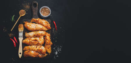Raw marinated chicken breast on dark background with spices ready to cook. Banner.の写真素材