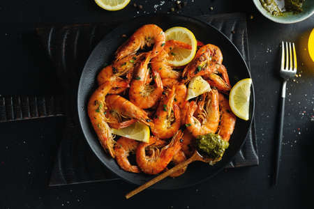 Tasty shrimps with spices and sauce on plate on dark background. Top view.の写真素材