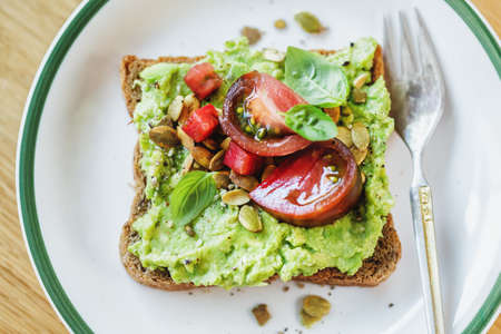 Tasty sandwich on wholegrain bread with mashed avocado and tomatoes. Closeup.の写真素材