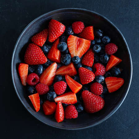 Fresh summer berries on plate on dark background. Square.の写真素材