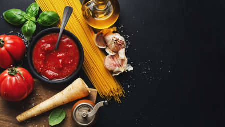 Italian food background with vegetables and tomato sauce on dark background. Top view.の写真素材