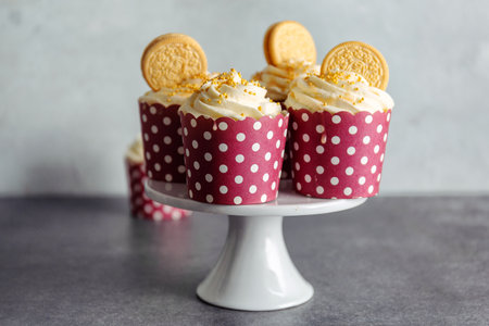Vanilla cupcakes with cream and caramel on gray table background.