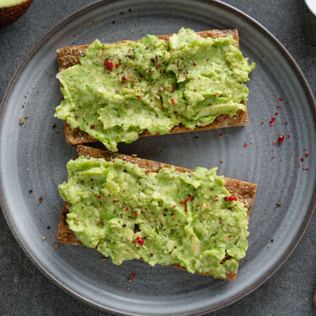 Tasty appetizing crispbread with mashed avocado served on plate. Squareの写真素材