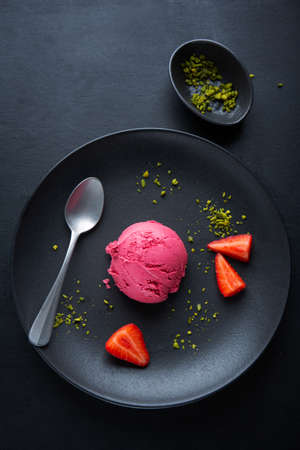 Fruity strawberry Ice cream scoops with strawberry sauce served on plate with fruits and pistacchios. Top View.の写真素材