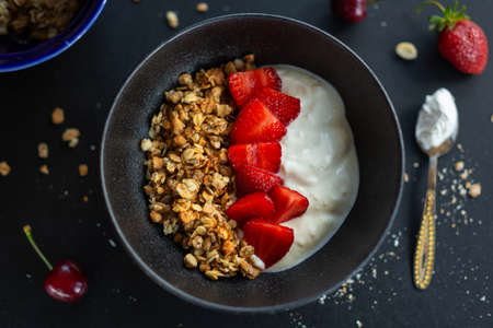 Tasty homemade fruity muesli granola served in bowl with yogurt on dark background. Closeupの写真素材