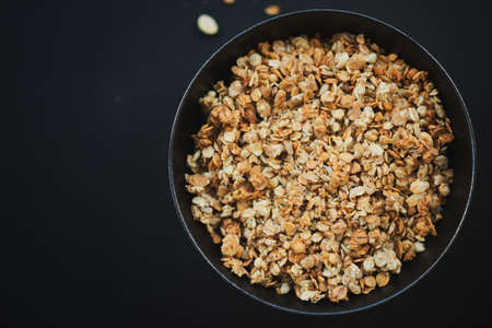 Tasty homemade muesli granola served in bowl on dark background. Closeup