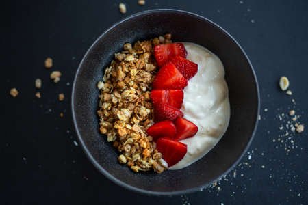 Tasty homemade fruity muesli granola served in bowl with yogurt on dark background. Closeupの写真素材