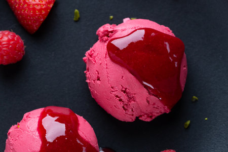 Fruity strawberry Ice cream scoops with strawberry sauce served on plate with fruits and pistacchios. Top View.の写真素材