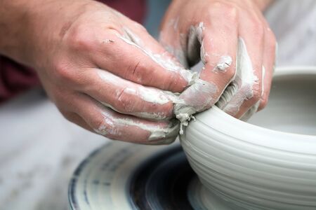 Hands of a potter creating a gray bowl.の写真素材