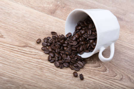 Coffee spill out of a white cup on wooden backgroundの写真素材